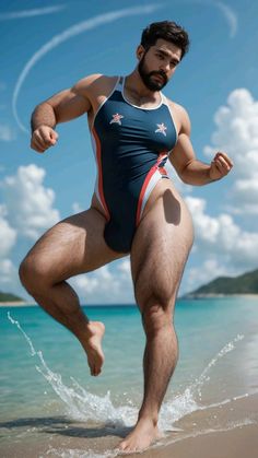 a man standing on top of a sandy beach next to the ocean wearing a blue and red swimsuit