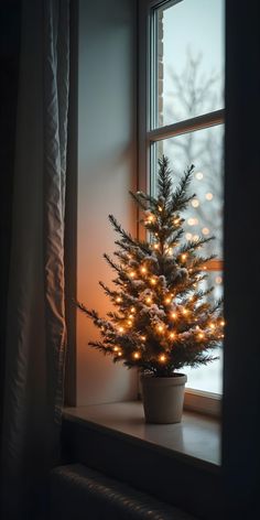 a small christmas tree sitting on top of a window sill next to a window