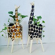 two giraffe planters with plants in them on top of white wooden legs