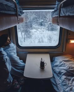 there is a small table with a cup on it next to the window in the cabin