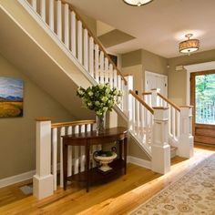 an entryway with stairs leading up to the second floor and a painting on the wall