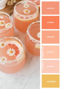 three glasses filled with drinks sitting on top of a table next to flowers and fruit