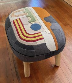 a small foot stool made out of patchwork fabric and wooden legs on a hard wood floor