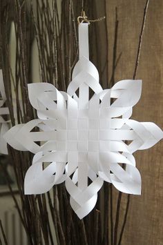 a paper snowflake ornament hanging from a tree