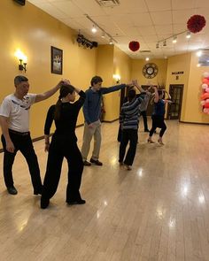 a group of people standing on top of a hard wood floor in a dance studio