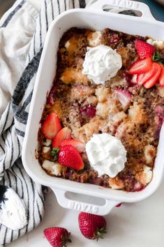 a casserole dish with strawberries and whipped cream on top, ready to be eaten