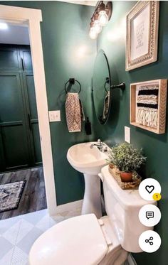 a bathroom with green walls and pictures on the wall above the toilet, sink and mirror