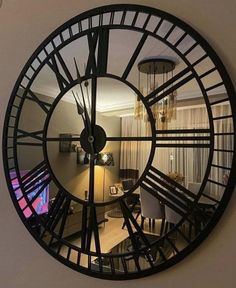 a large black clock mounted to the side of a wall next to a living room