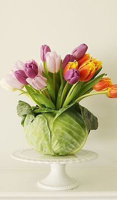 a vase filled with colorful tulips sitting on top of a white tablecloth