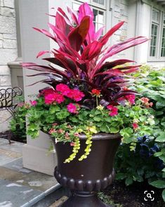 a large potted planter filled with flowers on the side of a house's front porch