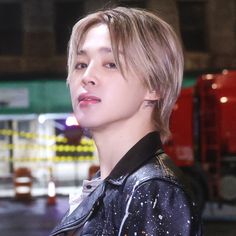 a young man with short hair and piercings on his ears standing in front of a fire truck