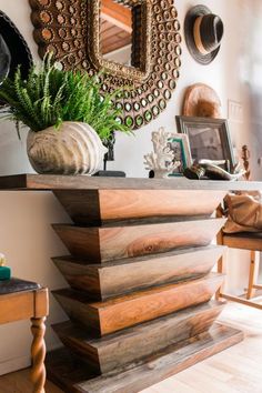 a wooden table topped with a potted plant next to a mirror