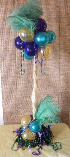 a palm tree made out of balloons and beads on a bed with a wall in the background