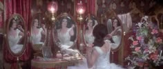 a woman in a white dress is looking at herself in the mirror