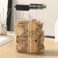 a clear plastic container filled with cookies on top of a wooden table next to a computer