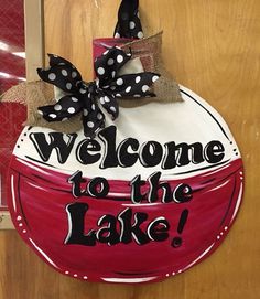 a welcome to the lake sign hanging on a door with burlocks and bows