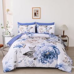 a blue and white flowered comforter set on a bed with matching pillow cases