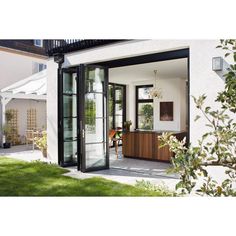 an open patio door leading into a white house with black glass and wood trimmings