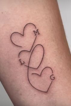 a small tattoo on the leg of a woman with two hearts and a letter m