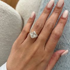 a woman's hand with a diamond ring on her finger and the other hand holding an engagement ring