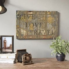 a wooden table topped with books next to a vase filled with plants and pictures on top of it