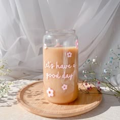 a glass jar with some writing on it sitting on a wooden tray next to flowers