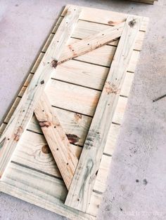 an unfinished wooden door sitting on top of a cement floor next to a piece of wood