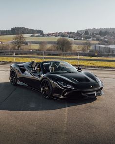 a black sports car parked on the side of the road in front of a field