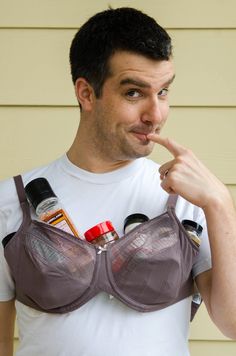 a man wearing a bra and pointing to the side with his finger in his mouth