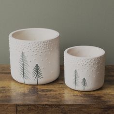 two white bowls with trees painted on them sitting on a wooden table next to each other