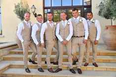 a group of men standing next to each other in front of a door wearing tan suits