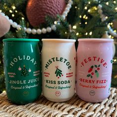 three different types of holiday beverages sitting next to a christmas tree