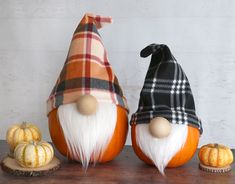 two gnomes sitting next to each other on top of a wooden table with pumpkins