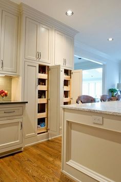 a large kitchen with white cabinets and wood flooring, along with an island in the middle