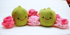 three stuffed toys are sitting on a white surface with pink and green flowers in the foreground