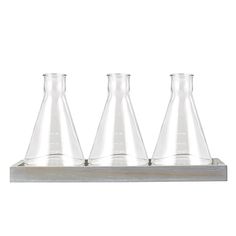 three glass flasks sitting on top of a wooden shelf