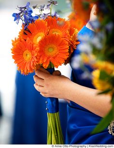 a woman holding a bouquet of orange and blue flowers