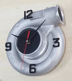 a metal clock with red hands and numbers on it