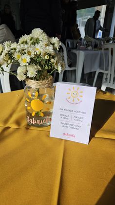 a vase filled with white flowers sitting on top of a yellow table cloth covered table