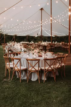 an outdoor tent with tables and chairs set up for a wedding reception in the grass