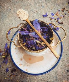 a bowl filled with purple flowers and two wooden spoons sitting on top of it