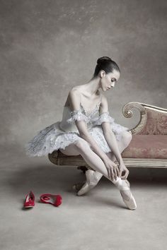 a woman sitting on top of a bed next to red shoes