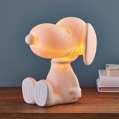 a white dog lamp sitting on top of a wooden table next to a stack of books