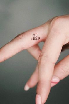 a small butterfly tattoo on the middle finger