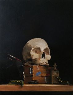 a skull sitting on top of a wooden table next to a bottle and other items