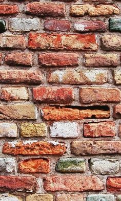 an old brick wall with several different colored bricks on the top and bottom, as well as small holes in the middle