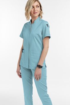 The UA Butter-soft Stretch women s 6-pocket collar neck zip front scrub top scrub top features a modern fit with a stand collar style and concealed zipper with top-button closure for a sleek appearance. There are 6 pockets total; 4 flattering angled roomy front pockets and 2 pen pockets on wearers left sleeve for easy access. It has a three piece back panel for fit and comfort, as well as side vents for ease of movement. Fabric is made up of 55 42 3 cotton poly spandex. • Modern fit • Stand Coll Cheap Gray Blouse For Workwear, Uniform Advantage Scrubs For Women, Yoga Scrub Pants, Scrub Jackets, Collar Neck