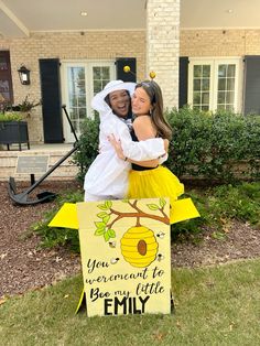 two people dressed up in costumes standing next to a sign that says you were meant to be my little envy