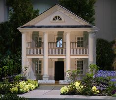 a doll house is shown with flowers around it