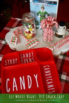 a red tray with candy canes and candies on it next to a book